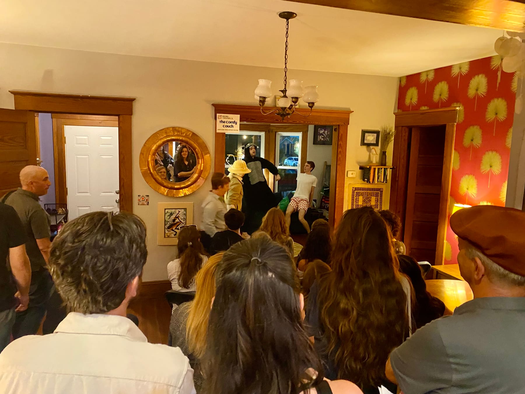 A packed living room crowds around The Comfy Couch venue as a performer in a gorilla suit lunges at an actor in heart-print boxers