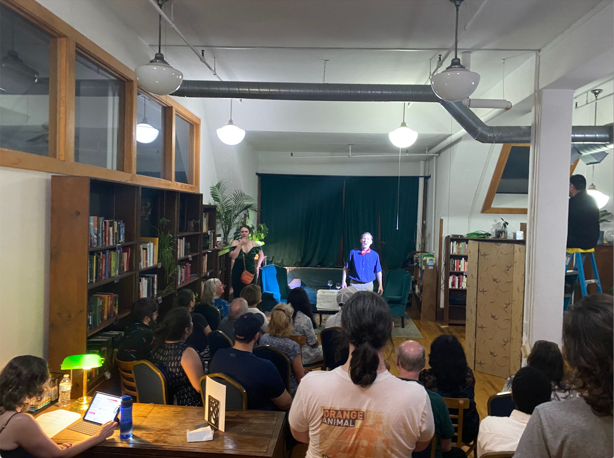 Performance in library space with audience seated at tables