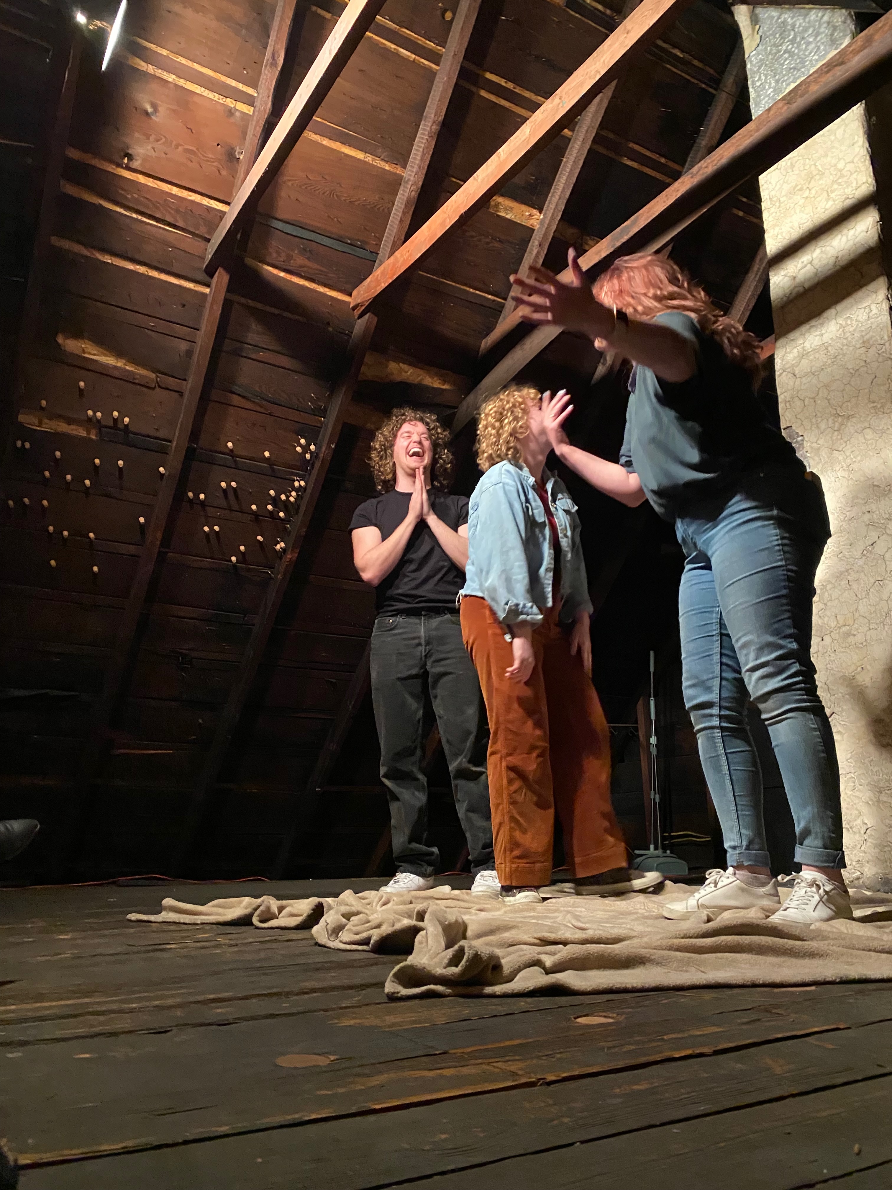 Performers in an atmospheric attic space with exposed beams